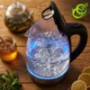 Gros plan sur l'eau bouillante et les graduations de cette bouilloire electrique verre lumineuse bleue sur table en bois