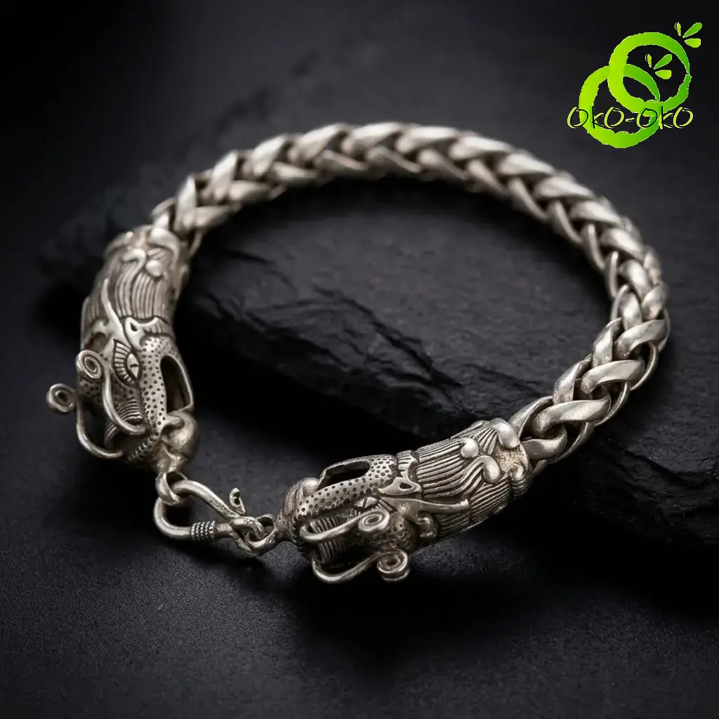 Bracelet dragon en argent tibétain | OkO-OKO™ Gros plan sur la tête sculptée d'un bracelet dragon en argent tibétain posé sur une pierre noire texturée sombre