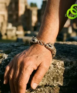 Gros plan sur un bracelet dragon en argent tibétain porté au poignet, posé sur une pierre ancienne au soleil