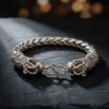 Bracelet dragon en argent tibétain | OkO-OKO™ Gros plan sur le fermoir crochet d'un bracelet dragon en argent tibétain au design tressé posé sur roche noire sombre