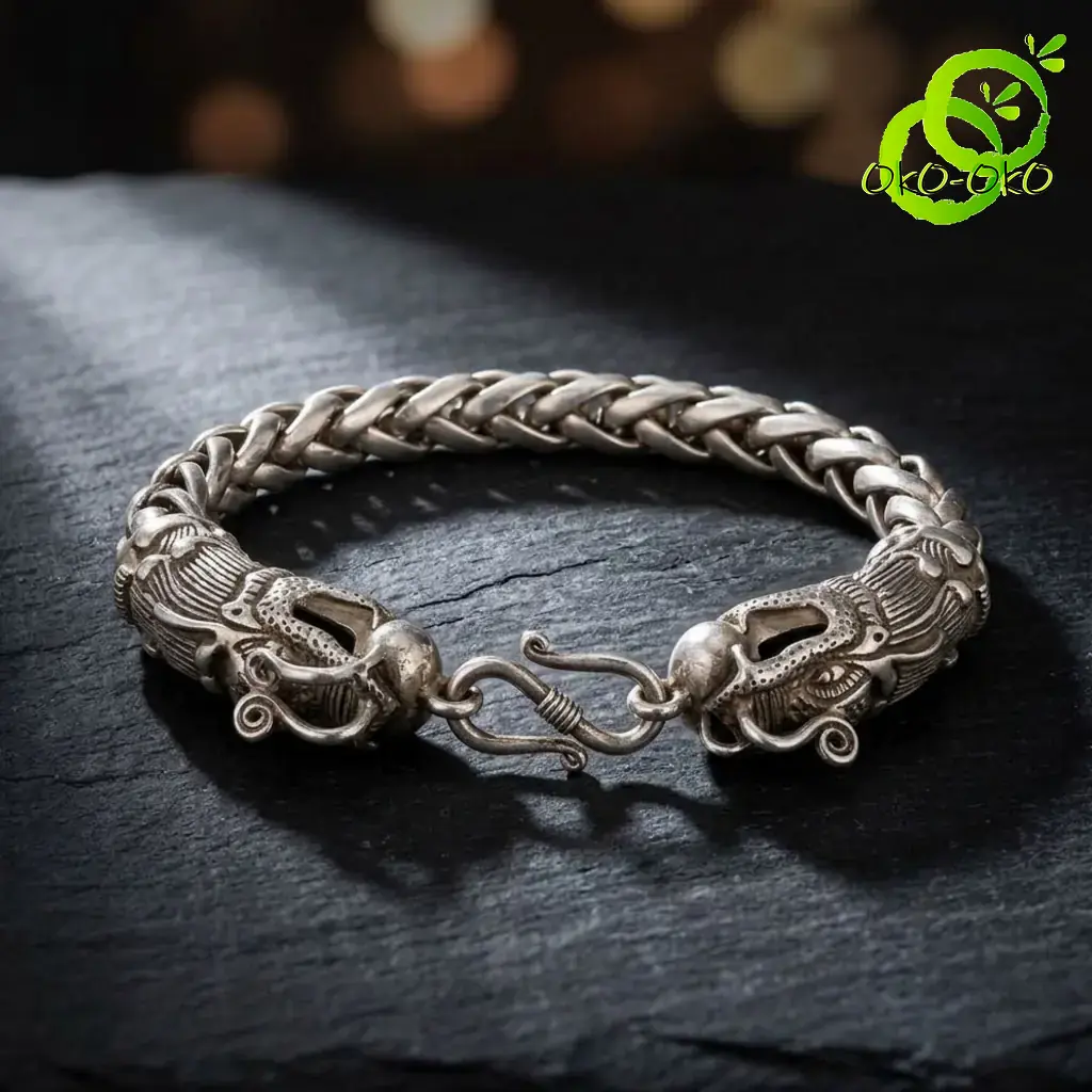 Bracelet dragon en argent tibétain | OkO-OKO™ Gros plan sur le fermoir crochet d'un bracelet dragon en argent tibétain au design tressé posé sur roche noire sombre
