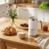 Mousseur lait electrique chauffe blanc avec écran numérique LCD posé sur table en bois près d'un café latte et croissant