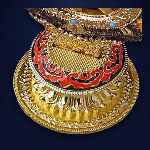 Roue du Dharma dorée ou Dharmachakra aux détails précieux et dorés | OkO-OKO™ Close-up of the ornate gold base of a roue dharma doree dharmachakra featuring red enamel patterns and intricate carvings