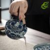 main versant du thé d'un service porcelaine bleu et blanc motif lotus traditionnel sur une tasse dans une ambiance calme