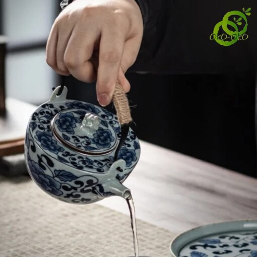 main versant du thé d'un service porcelaine bleu et blanc motif lotus traditionnel sur une tasse dans une ambiance calme