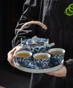 Service thé porcelaine bleu et blanc motif lotus traditionnel tenu par une main, détails des tasses et théière avec poignée en corde naturelle