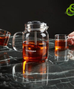théière verre filtre transparente avec système de filtration ascendant descendant sur table noire marbrée