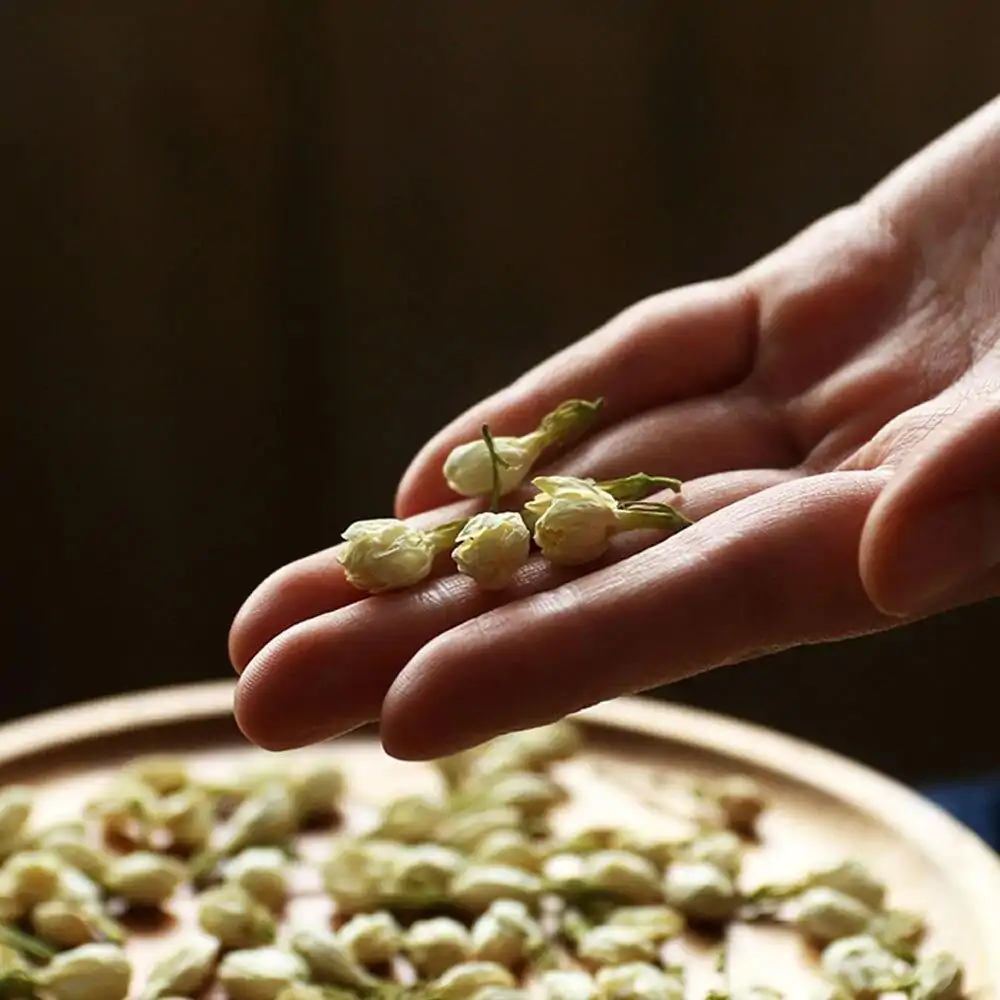 Thee en Infusie <br>Jasmijnbloem. | OkO-OKO™ Jasmijnbloementhee in houten bord met bloem in de hand| oko oko