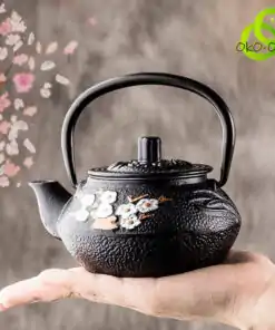 Teekanne-in-schwarzer-Schmelze-Kirschblüte-in-der-Hand oko-oko