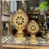 Roue du Dharma dorée ou Dharmachakra aux détails précieux et dorés | OkO-OKO™ Two sizes of gold plated roue dharma doree dharmachakra with ornate floral carvings displayed on a patterned rug