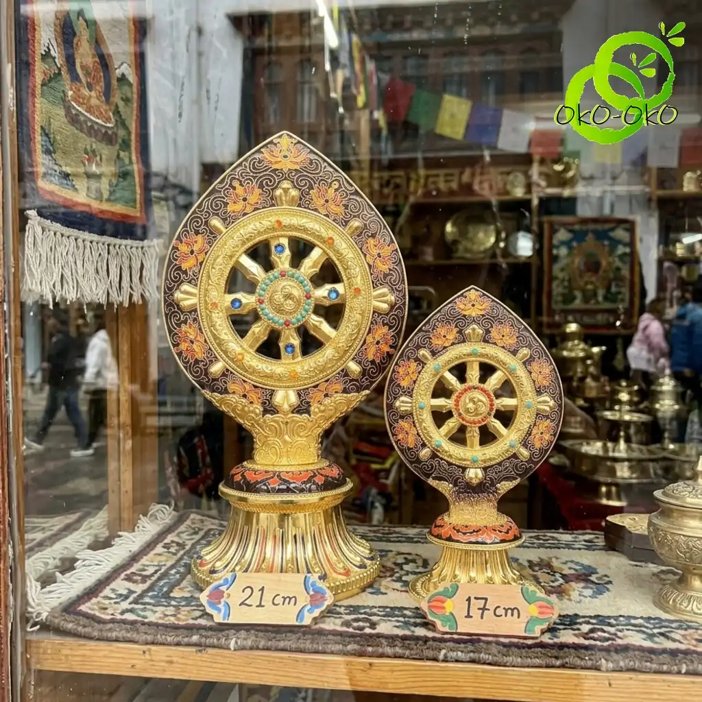 Roue du Dharma dorée ou Dharmachakra aux détails précieux et dorés | OkO-OKO™ Two sizes of gold plated roue dharma doree dharmachakra with ornate floral carvings displayed on a patterned rug