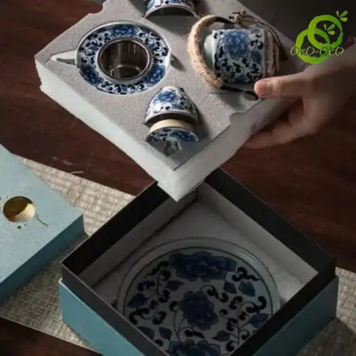 Blue and white porcelain tea set with a traditional lotus pattern | OkO-OKO™ A blue porcelain tea set with a delicate lotus pattern, elegantly presented in an open display box that reveals the teapot and delicate cups