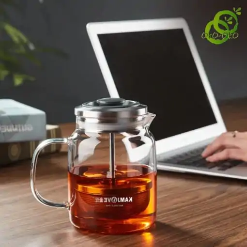 Glass Teapot with Retractable Filter | OkO-OKO™ théière verre filtre avec filtre descendant et remontant remplie d'infusion, sur table en bois avec ordinateur en arrière-plan